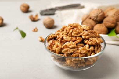 Photo of Tasty walnuts in bowl on grey table. Space for text
