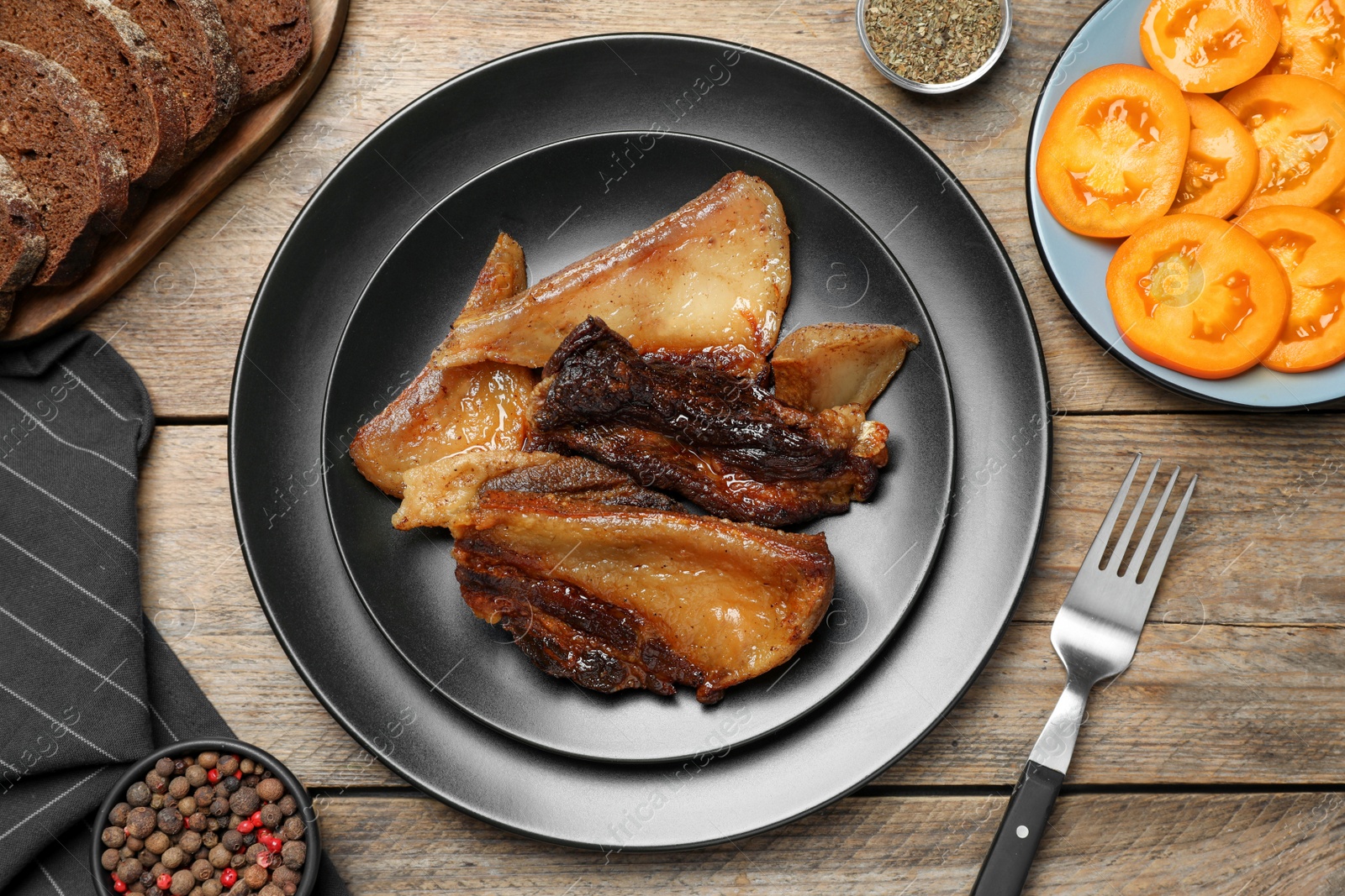 Photo of Tasty fried cracklings on wooden table, flat lay. Cooked pork lard