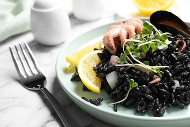 Photo of Delicious black risotto with seafood on white marble table, closeup