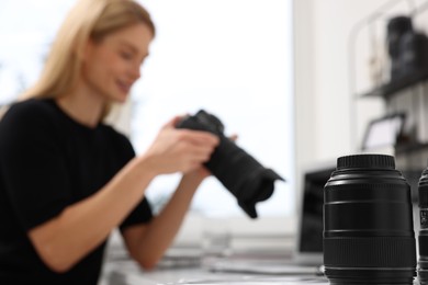 Photo of Professional photographer with digital camera at table indoors, focus on lenses
