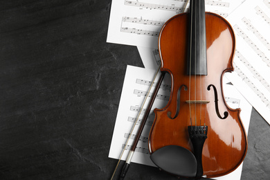 Violin, bow and note sheets on wooden table, flat lay. Space for text