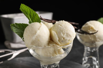 Photo of Tasty ice cream with vanilla pods and mint in glass dessert bowl on table, closeup