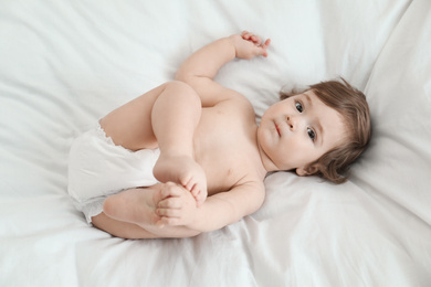 Cute little baby in diaper on bed, above view