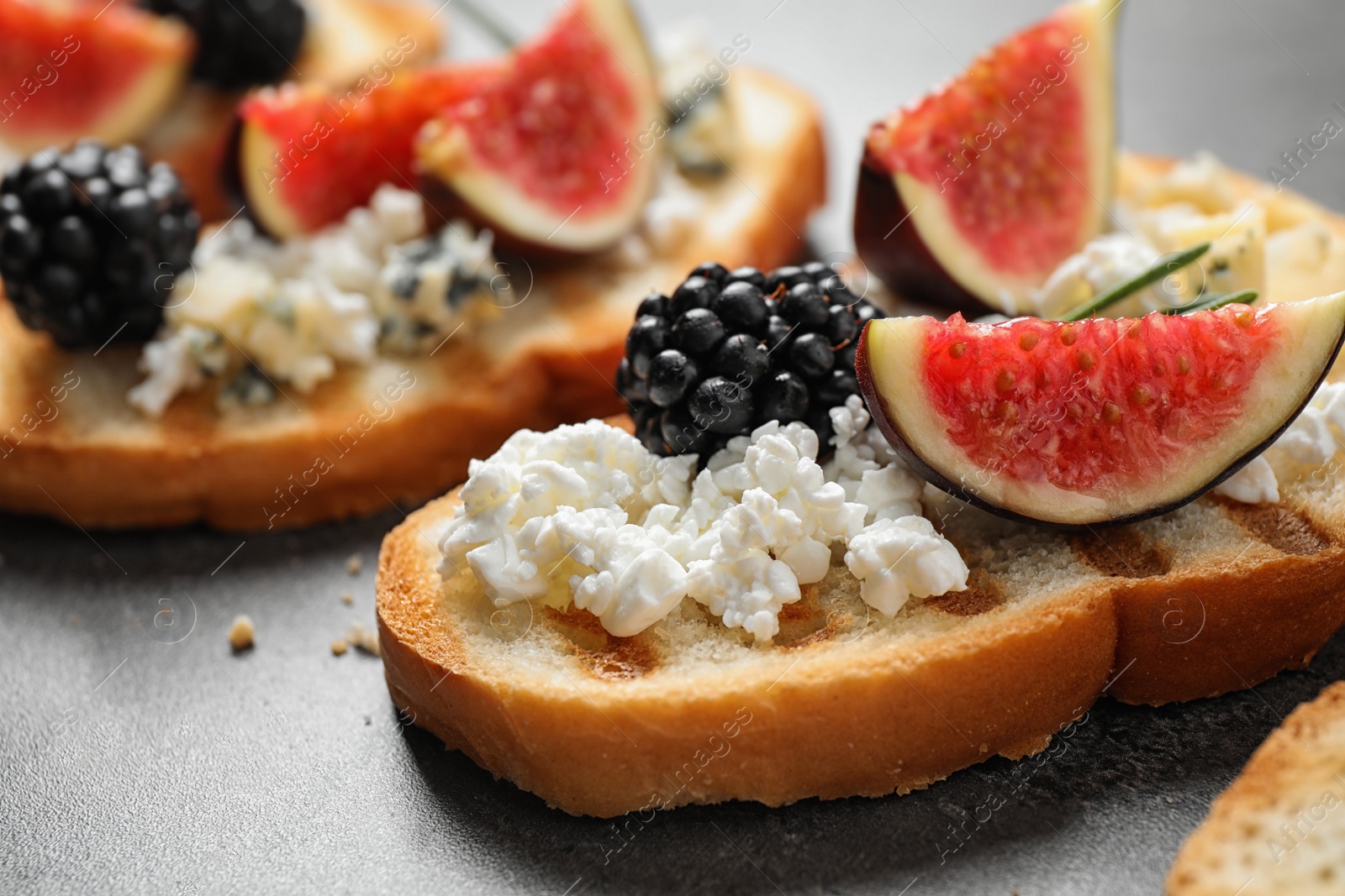 Photo of Bruschettas with cheese, figs and blackberries on grey table, closeup