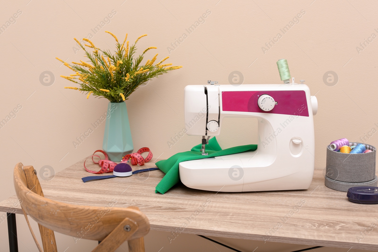 Photo of Modern sewing machine on table against light background