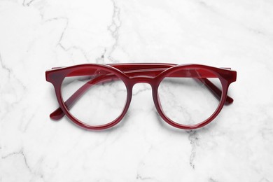 Glasses in stylish frame on white marble table, top view