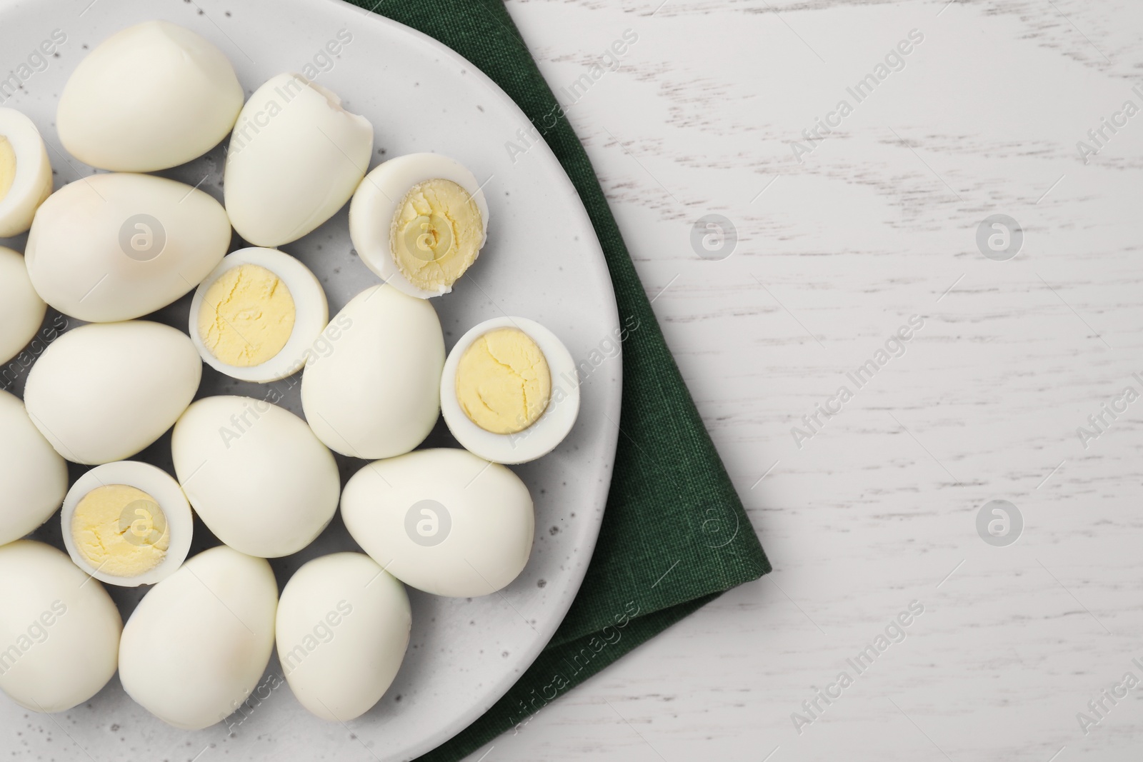 Photo of Many peeled hard boiled quail eggs on white wooden table, top view. Space for text