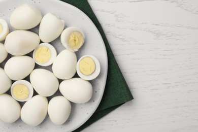Many peeled hard boiled quail eggs on white wooden table, top view. Space for text