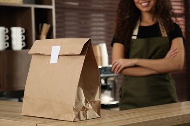 Worker near counter in cafe, focus on paper bag