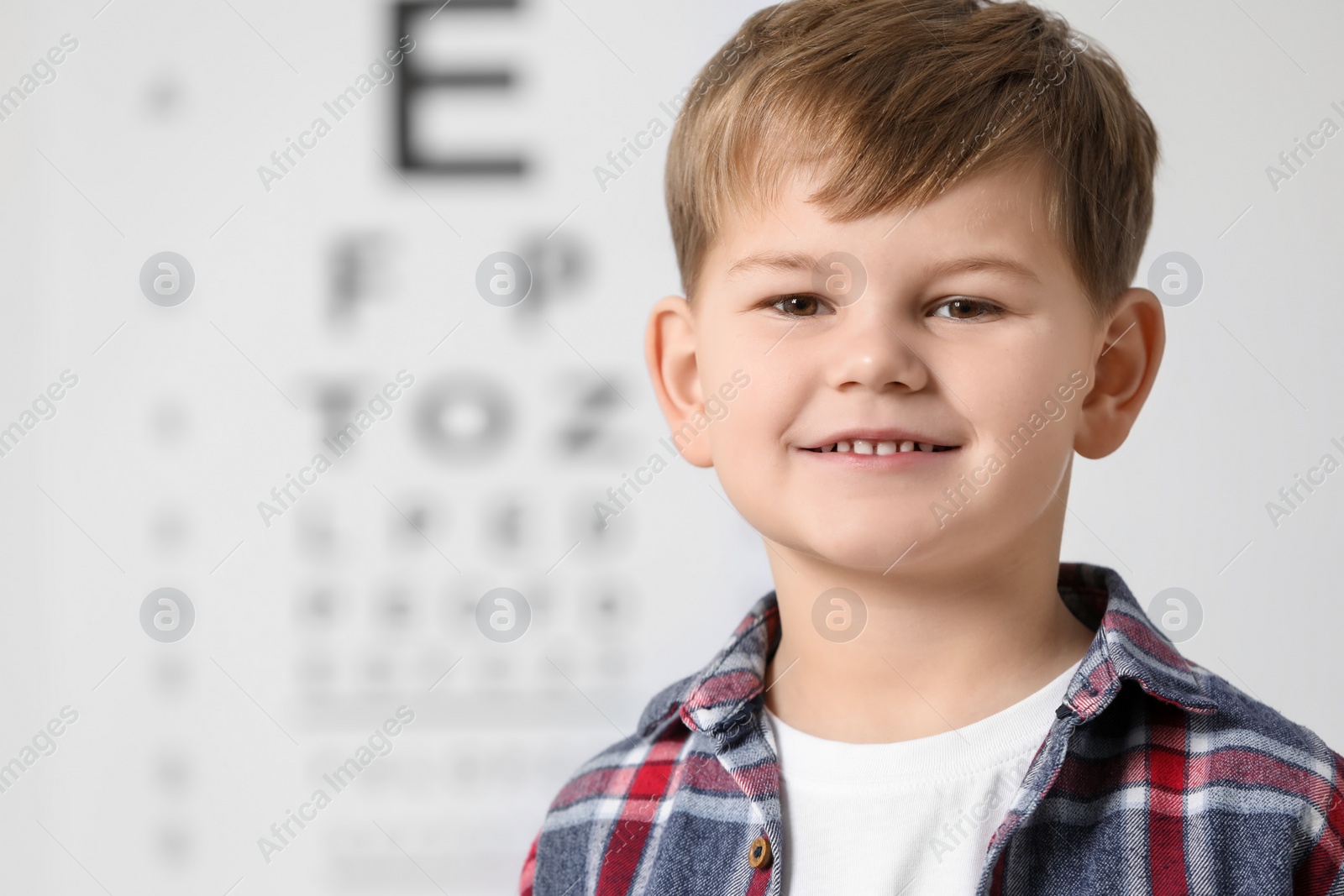 Photo of Cute little boy against vision test chart