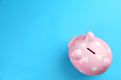 Pink piggy bank on blue background, top view. Space for text