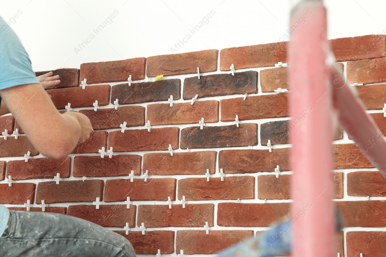 Photo of Professional builder gluing decorative brick on wall, closeup. Tiles installation process