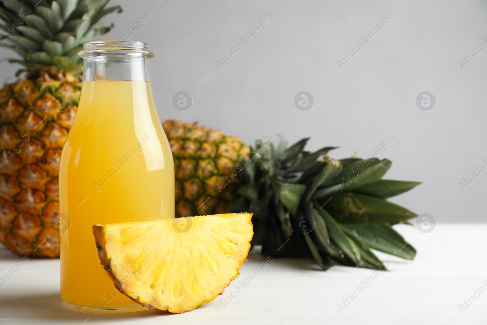 Photo of Delicious pineapple juice and fresh fruit on white wooden table