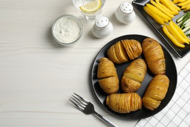 Delicious homemade Hasselback potatoes served on white wooden table, flat lay. Space for text