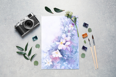 Photo of Flat lay composition with watercolor paints and floral picture on grey stone table
