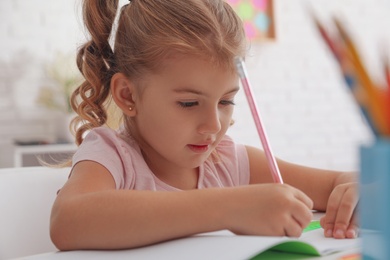 Cute little girl doing homework at table