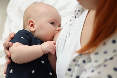 Mother breastfeeding her baby on bed, closeup