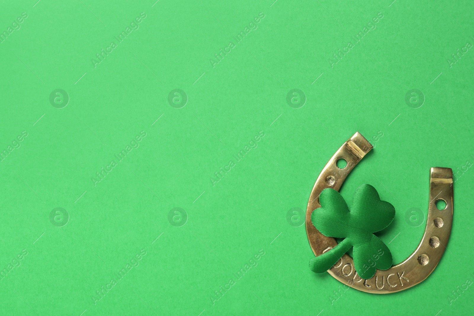 Photo of Decorative clover leaf and horseshoe on green background, flat lay with space for text. St. Patrick's Day celebration