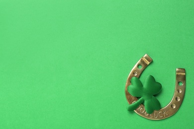 Decorative clover leaf and horseshoe on green background, flat lay with space for text. St. Patrick's Day celebration