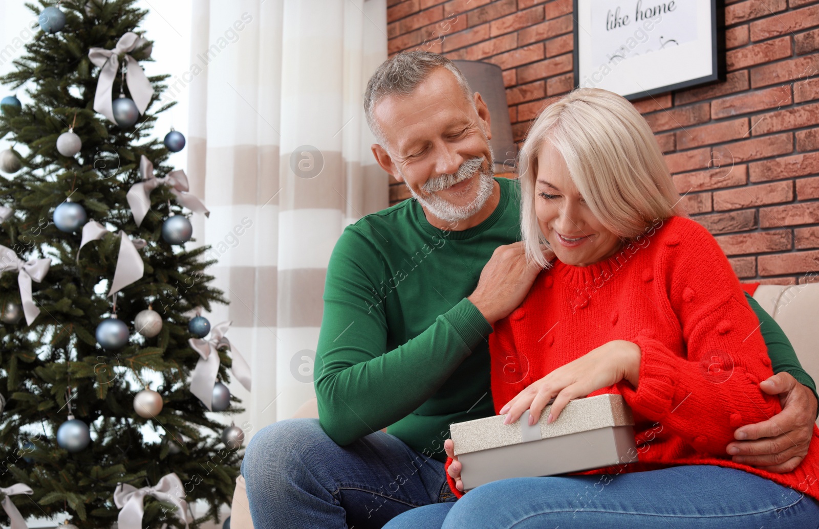 Photo of Mature couple with Christmas gift box at home