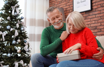 Mature couple with Christmas gift box at home