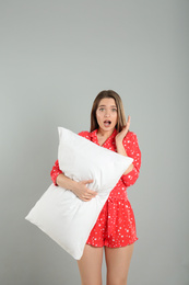 Photo of Shocked young woman with pillow on grey background