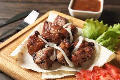 Photo of Wooden board with juicy shish kebab, closeup