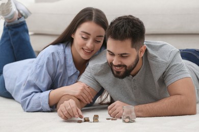 Photo of Happy young couple counting money on floor at home