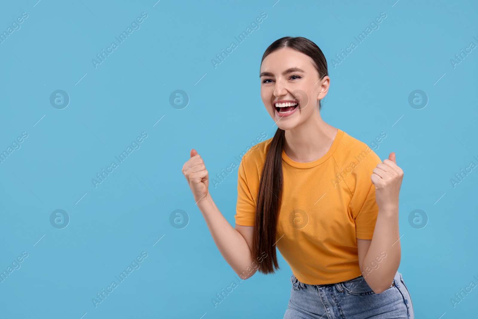 Photo of Happy sports fan celebrating on light blue background. Space for text