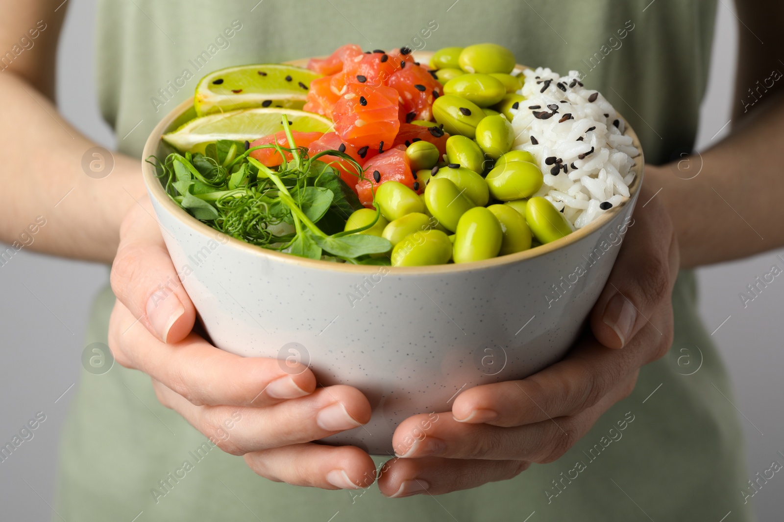 Photo of Woman holding delicious poke bowl quail eggs, fish and edamame beans, closeup