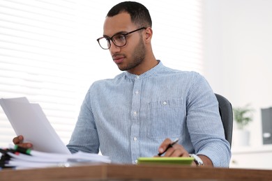 Photo of Businessman working with documents at wooden table in office