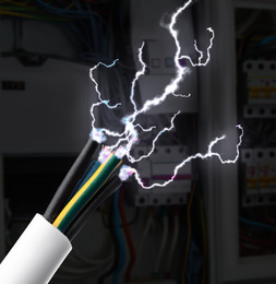 Image of Sparking cables against blurred electric cabinet, closeup