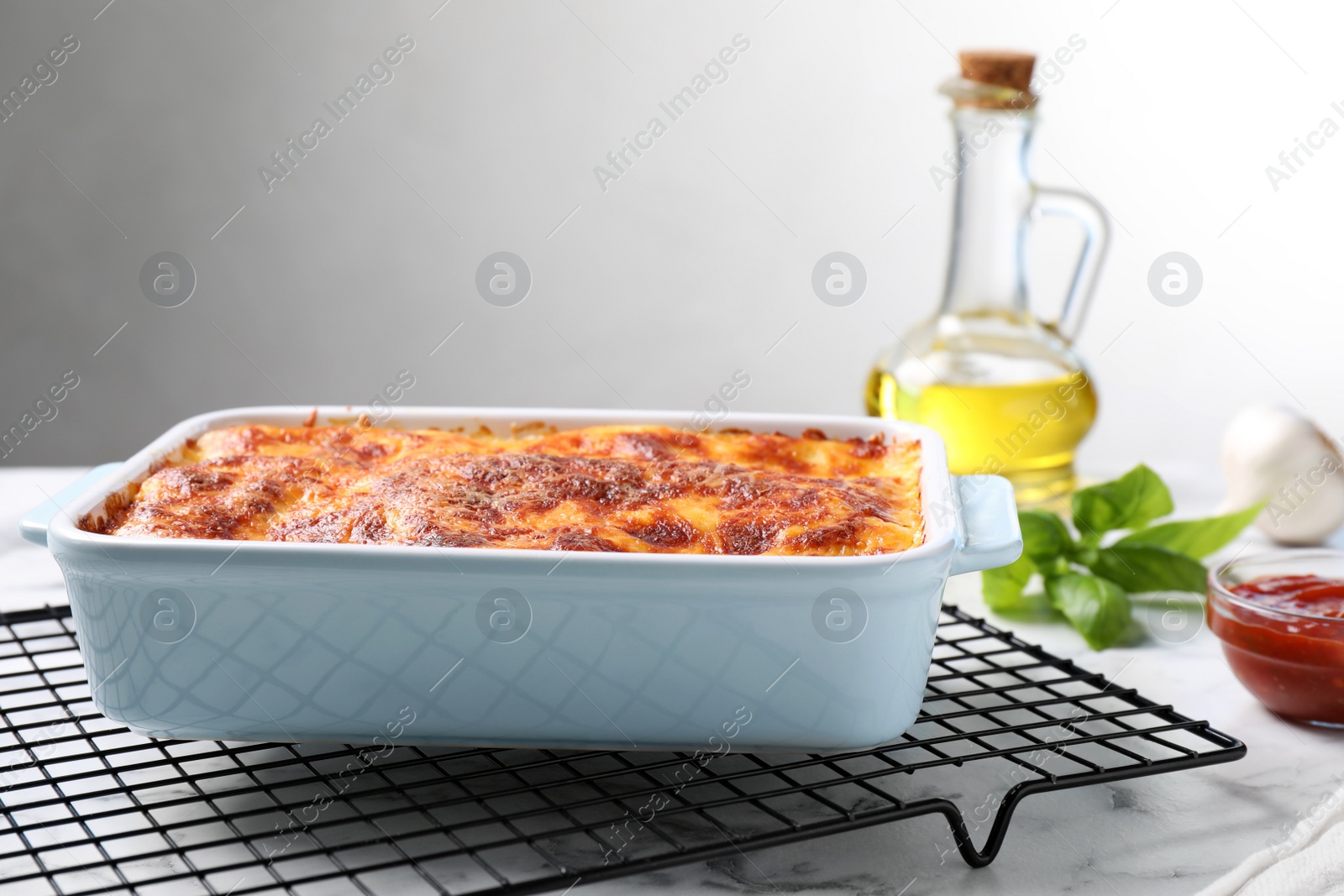 Photo of Tasty cooked lasagna in baking dish on white marble table