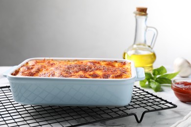 Tasty cooked lasagna in baking dish on white marble table
