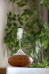 Photo of Aroma oil diffuser lamp on table against blurred background