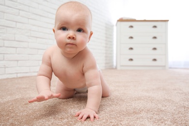 Photo of Cute little baby crawling on carpet indoors