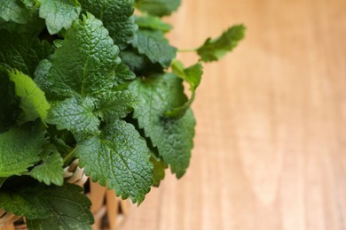 Fresh lemon balm on wooden table, closeup. Space for text