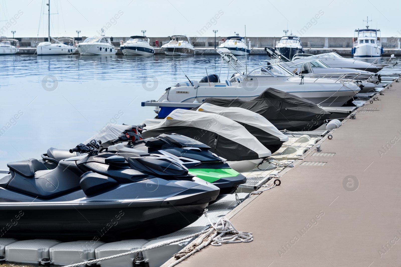 Photo of Beautiful view of city pier with water scooters and moored boats on sunny day