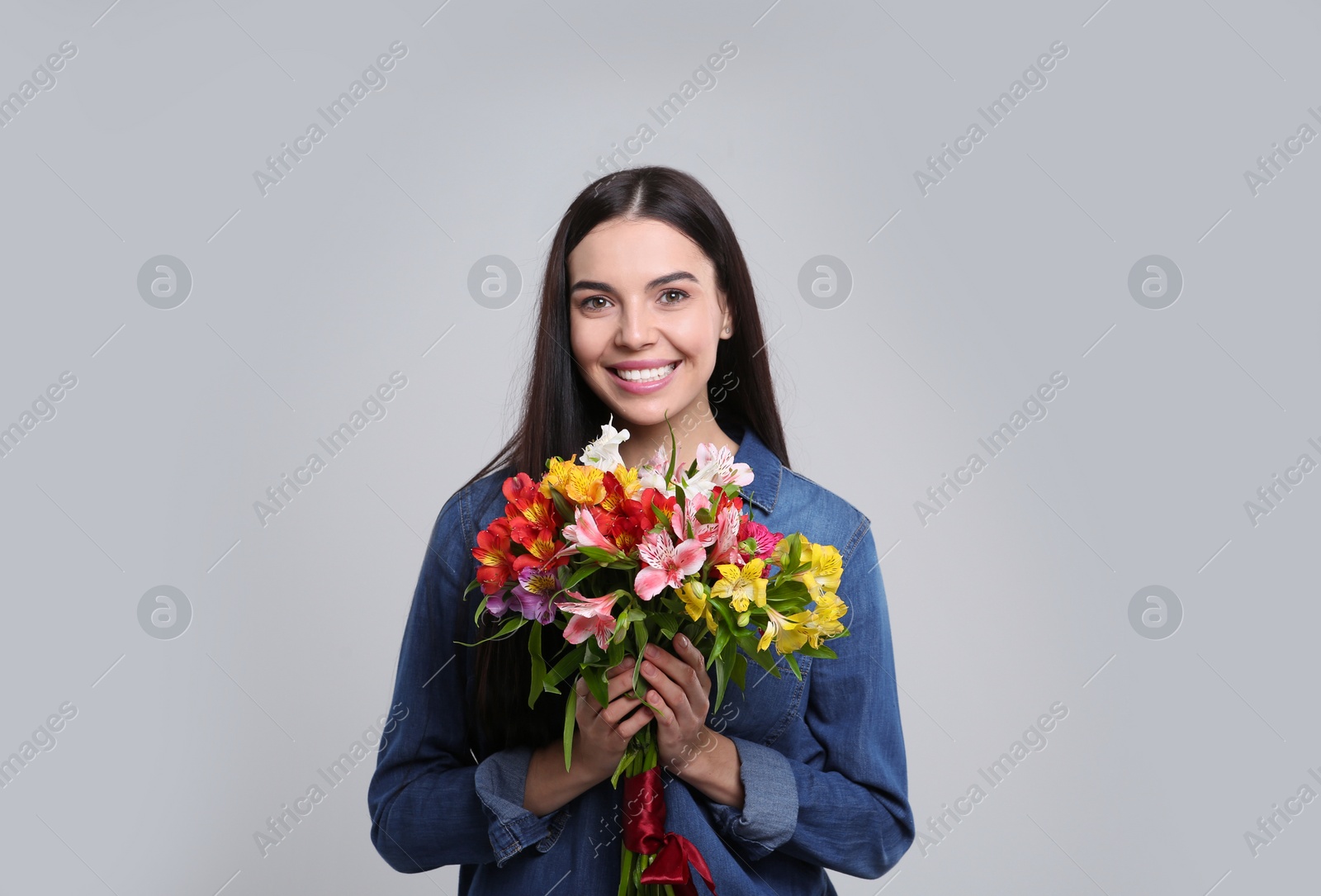 Photo of Happy young woman with beautiful bouquet on light grey background