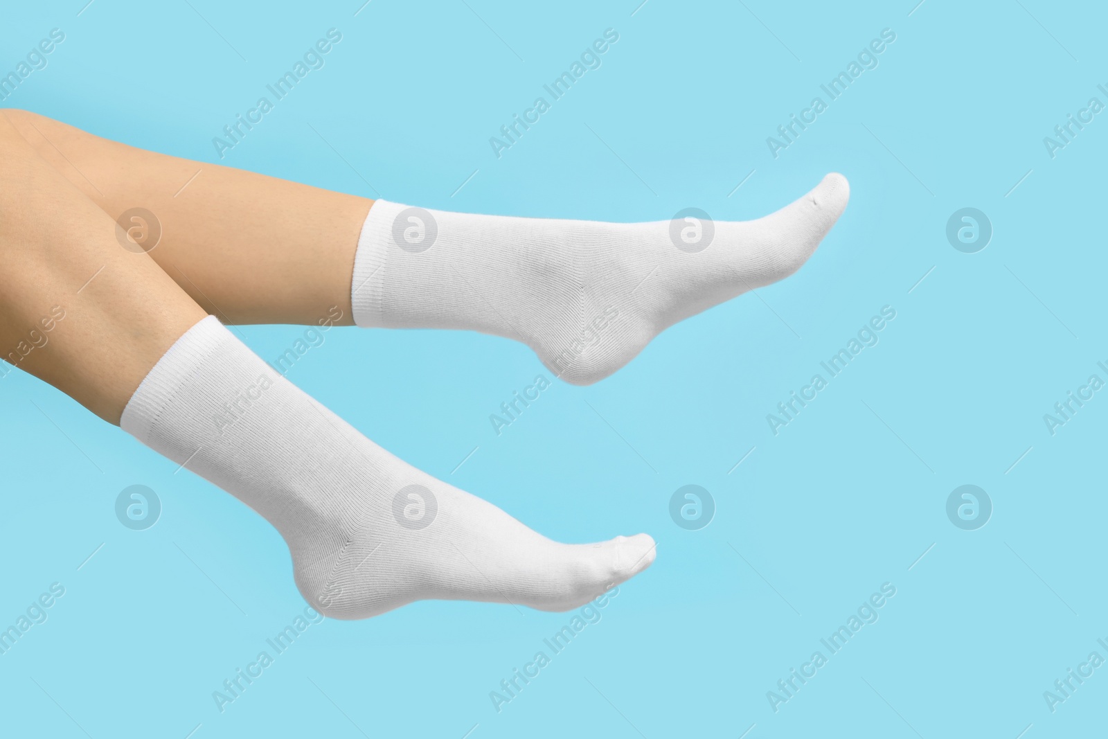 Photo of Woman in stylish white socks on light blue background, closeup