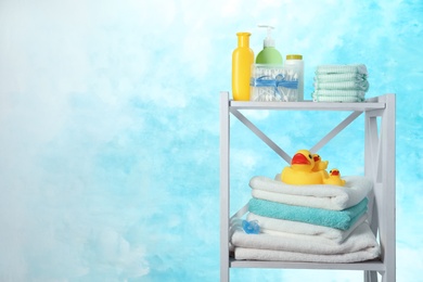 Photo of Shelving unit with different baby accessories on color background. Space for text
