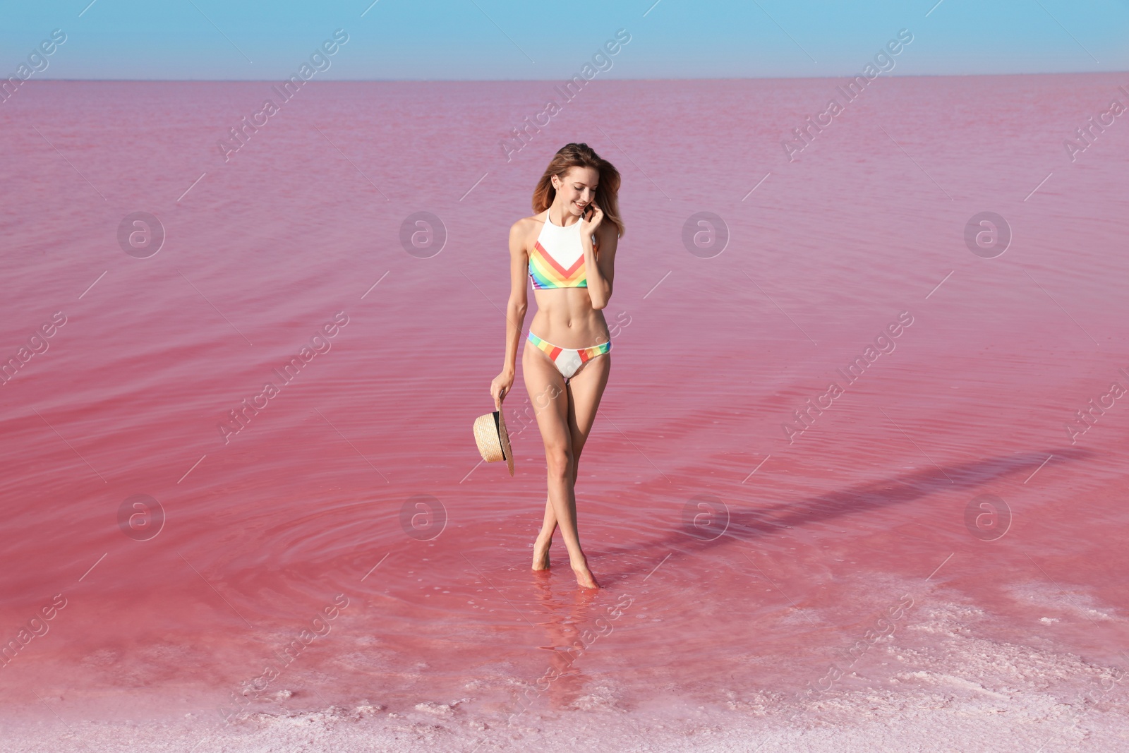 Photo of Beautiful woman in swimsuit posing near pink lake on sunny day