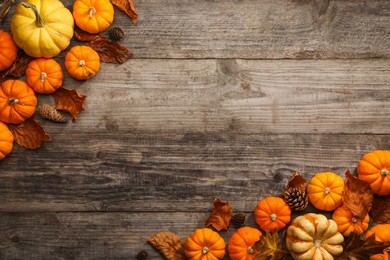 Photo of Dry autumn leaves, cones and pumpkins on wooden table, flat lay. Space for text
