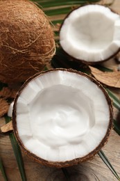 Photo of Ripe coconut with cream on wooden table, above view