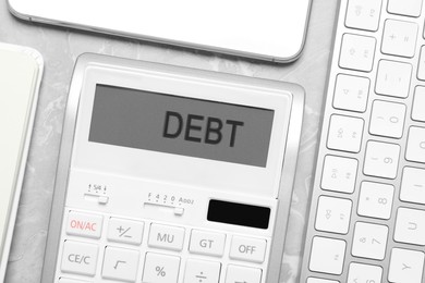 Calculator with word Debt on light grey marble table, flat lay