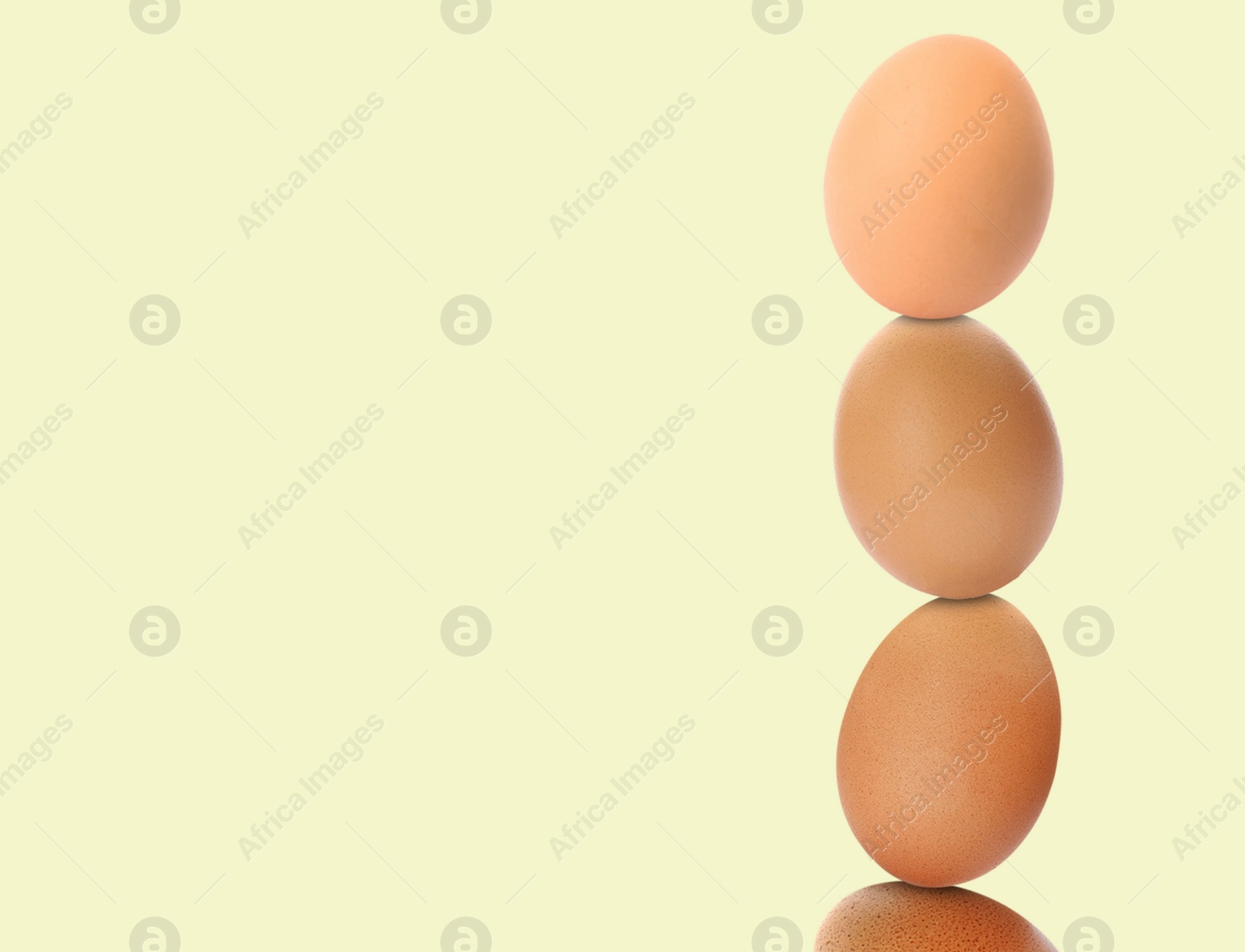 Image of Stacked fresh chicken eggs against light beige background. Space for text