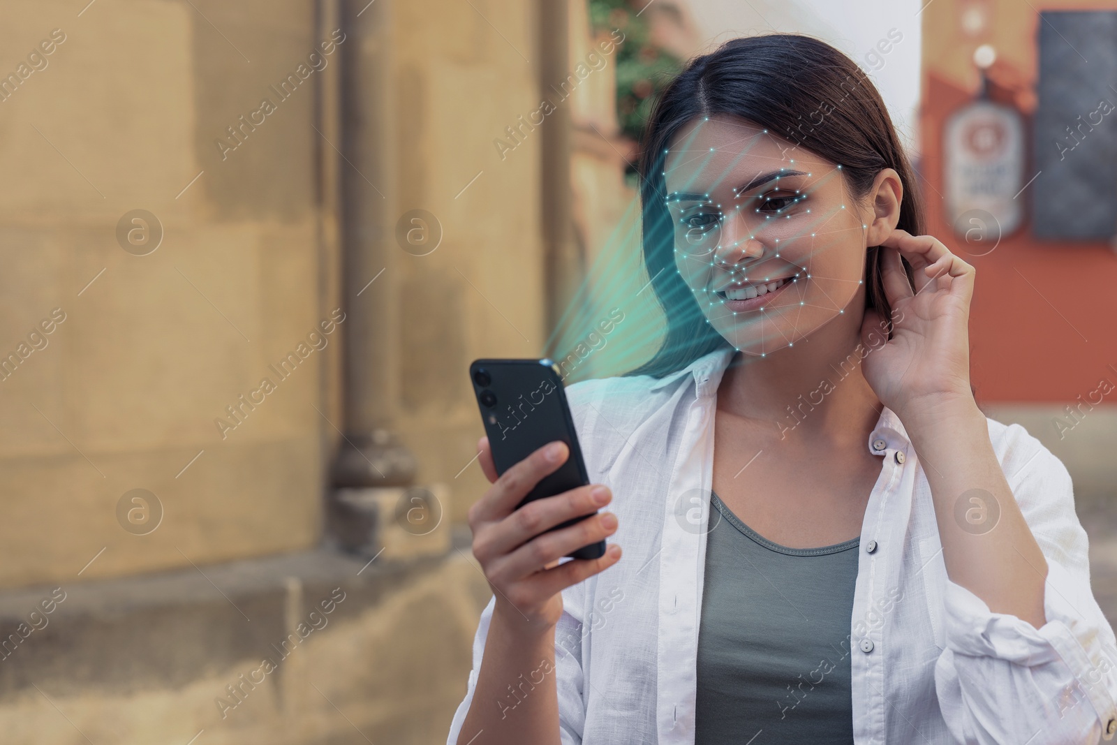 Image of Woman using smartphone with facial recognition system on street. Security application scanning her face for approving owner's identity
