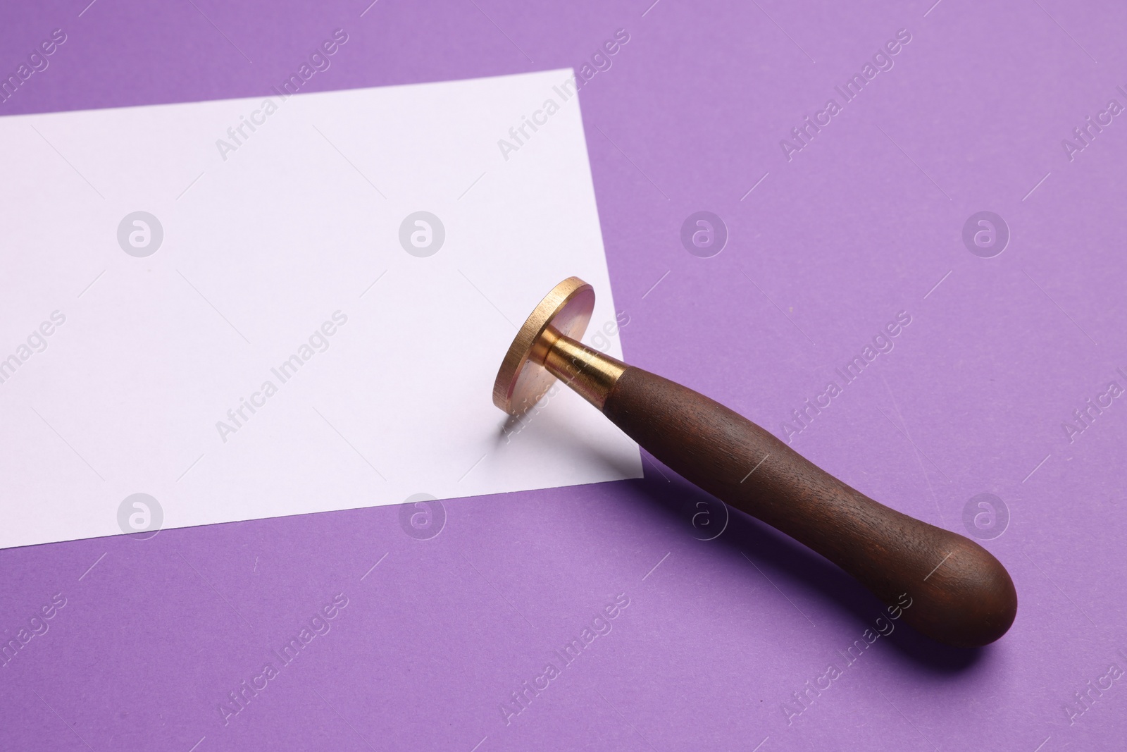 Photo of One stamp tool and sheet of paper on purple background