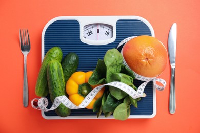 Photo of Scales, healthy food, measuring tape and cutlery on orange background, fat lay