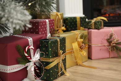 Photo of Many different gifts near Christmas tree and fireplace indoors